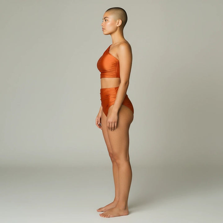 Sea Dragon Dreams high-waist bikini set in rust orange, featuring a one-shoulder top on a model, side profile view.