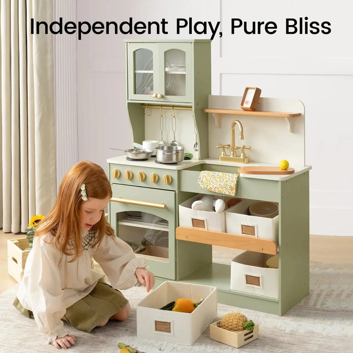 Sea Dragon Dreams Tiny Land wooden play kitchen in sage green with storage bins, cookware, and a young girl playing.