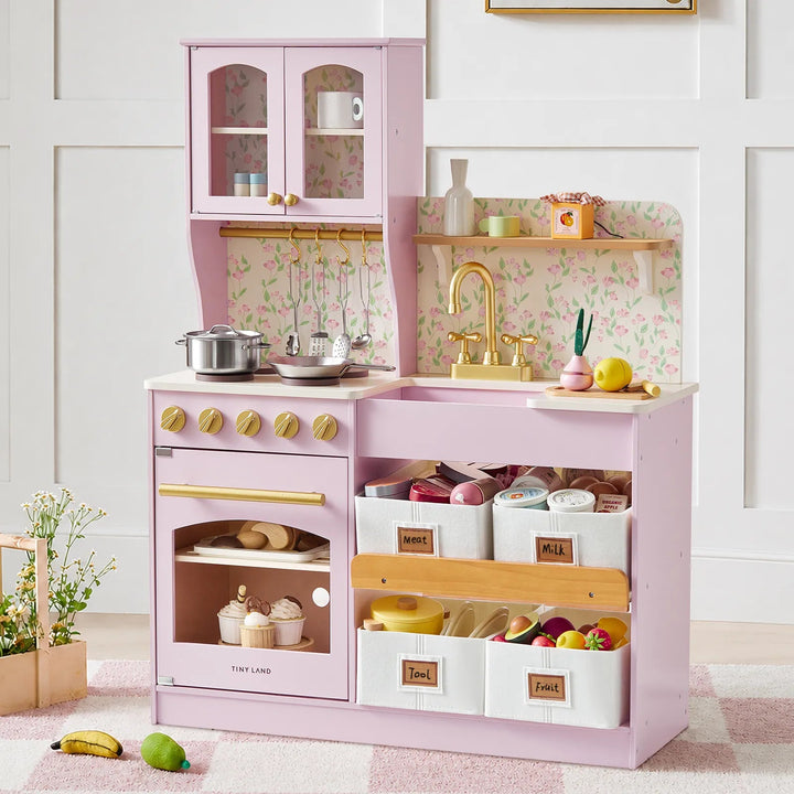 Sea Dragon Dreams Tiny Land wooden play kitchen in sakura pink with floral backsplash, gold faucet, and storage bins.