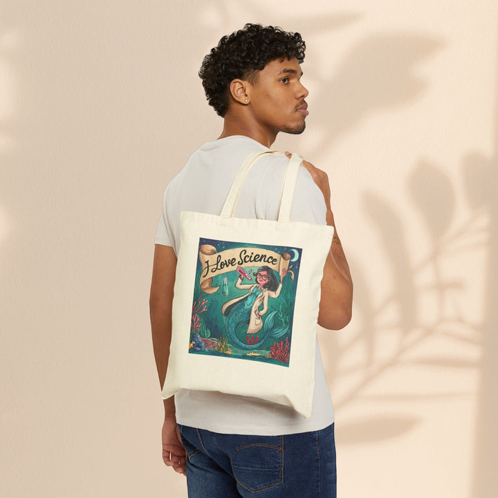 Sea Dragon Dreams cotton canvas tote bag with I Love Science mermaid illustration worn over shoulder by a man
