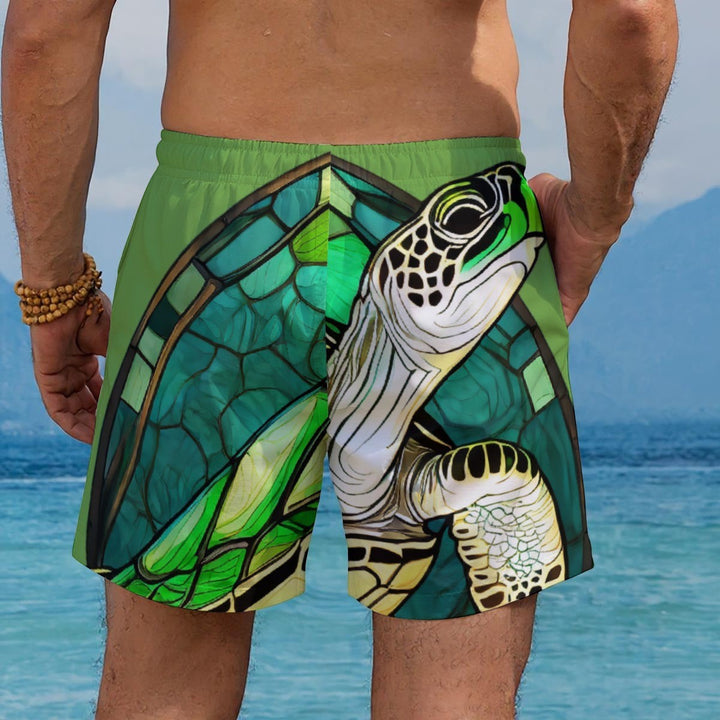 Sea Dragon Dreams men's Hawaiian shorts featuring a green stained-glass sea turtle design, worn at the beach.
