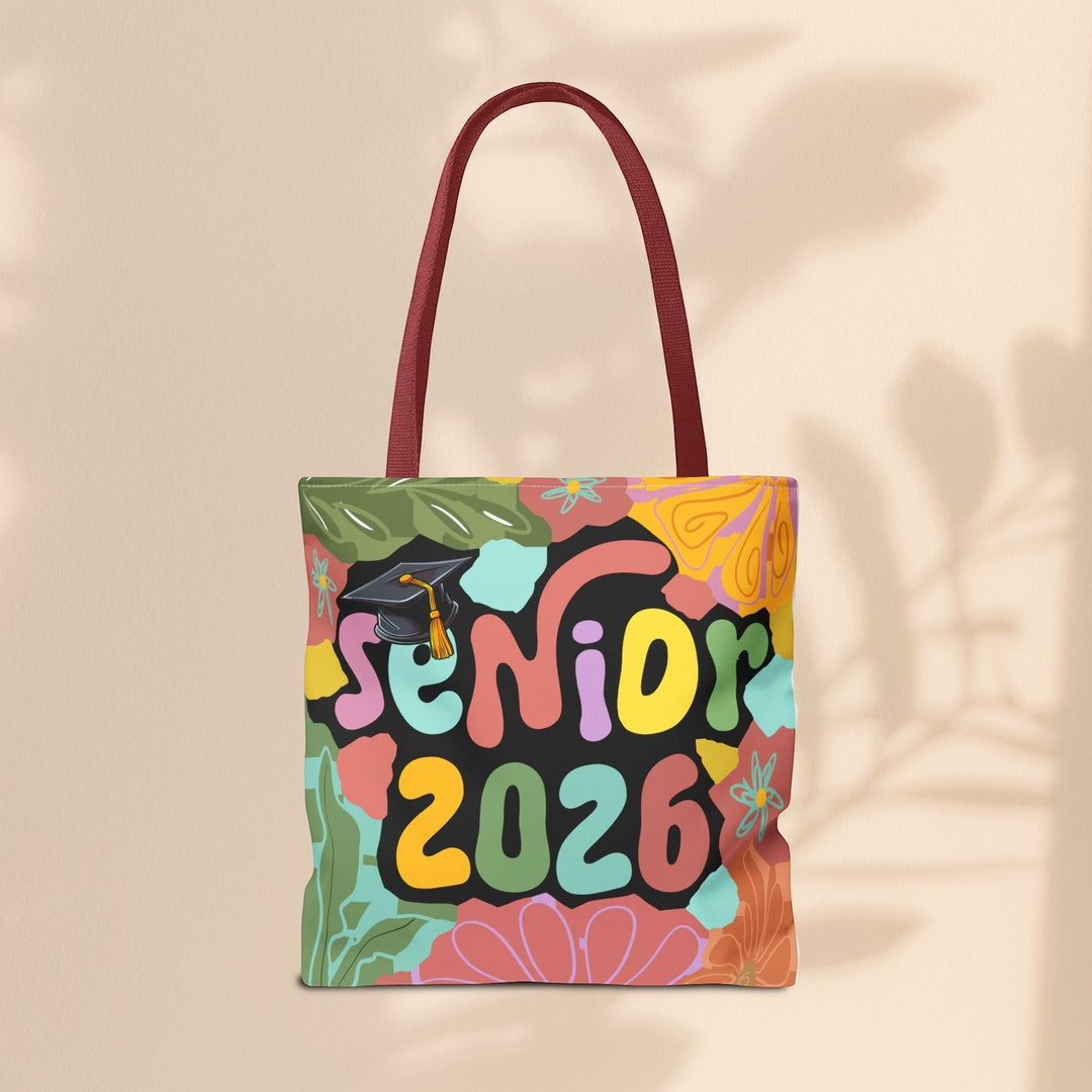 Sea Dragon Dreams Senior 2026 tote bag with colorful floral pattern, graduation cap graphic, and dark red handles.
