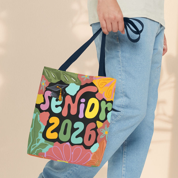 Sea Dragon Dreams Senior 2026 tote bag with colorful floral graduation design, held by a person in jeans.