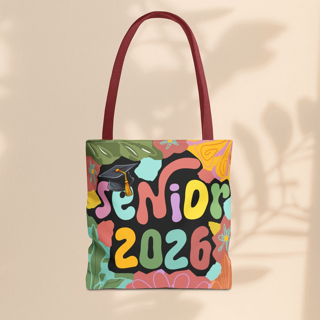Sea Dragon Dreams Senior 2026 tote bag with colorful retro floral print, graduation cap icon, and maroon handles.