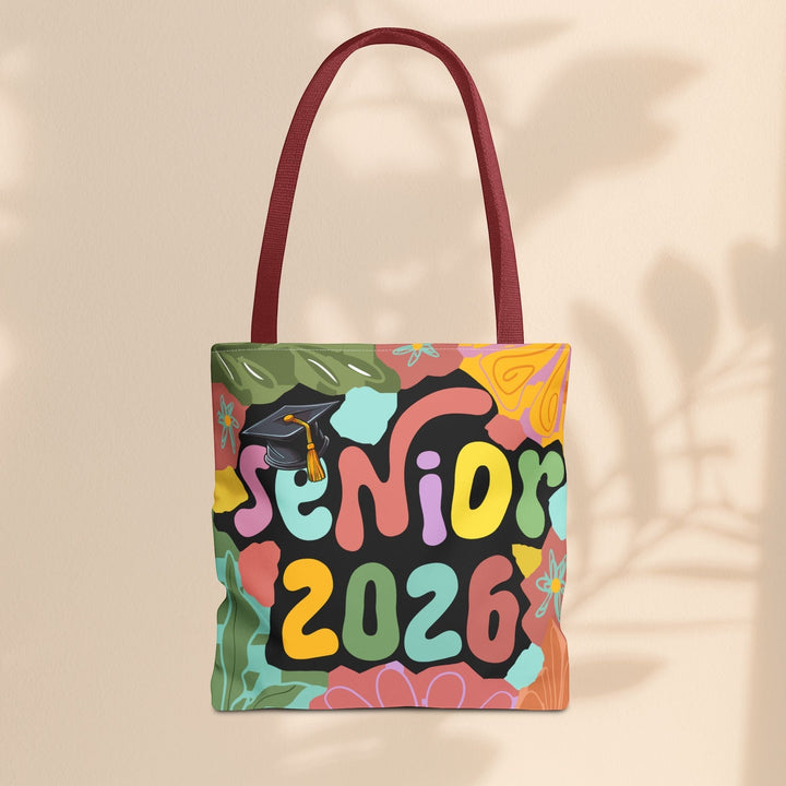 Sea Dragon Dreams Senior 2026 tote bag with colorful retro floral print, graduation cap icon, and maroon handles.