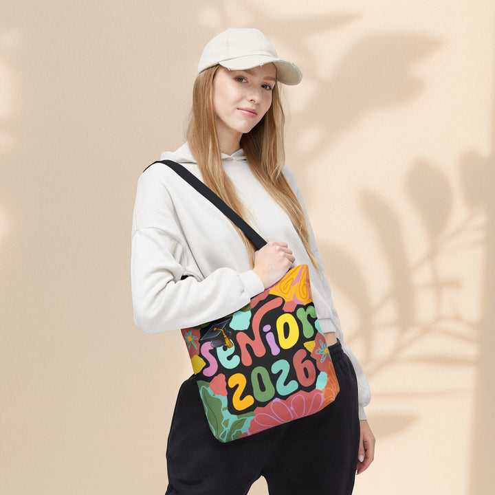 Sea Dragon Dreams Senior 2026 tote bag with colorful graphic print carried by a woman wearing a beige cap and hoodie.