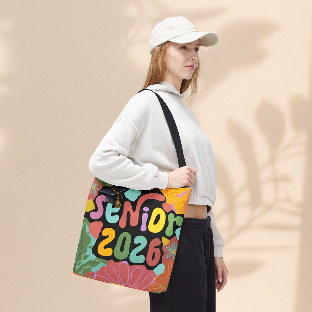 Sea Dragon Dreams Senior 2026 tote bag with colorful floral design and graduation cap, worn by a woman in a hoodie.