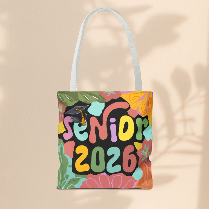 Sea Dragon Dreams Senior 2026 tote bag with colorful floral patterns and a graduation cap design on a beige background.