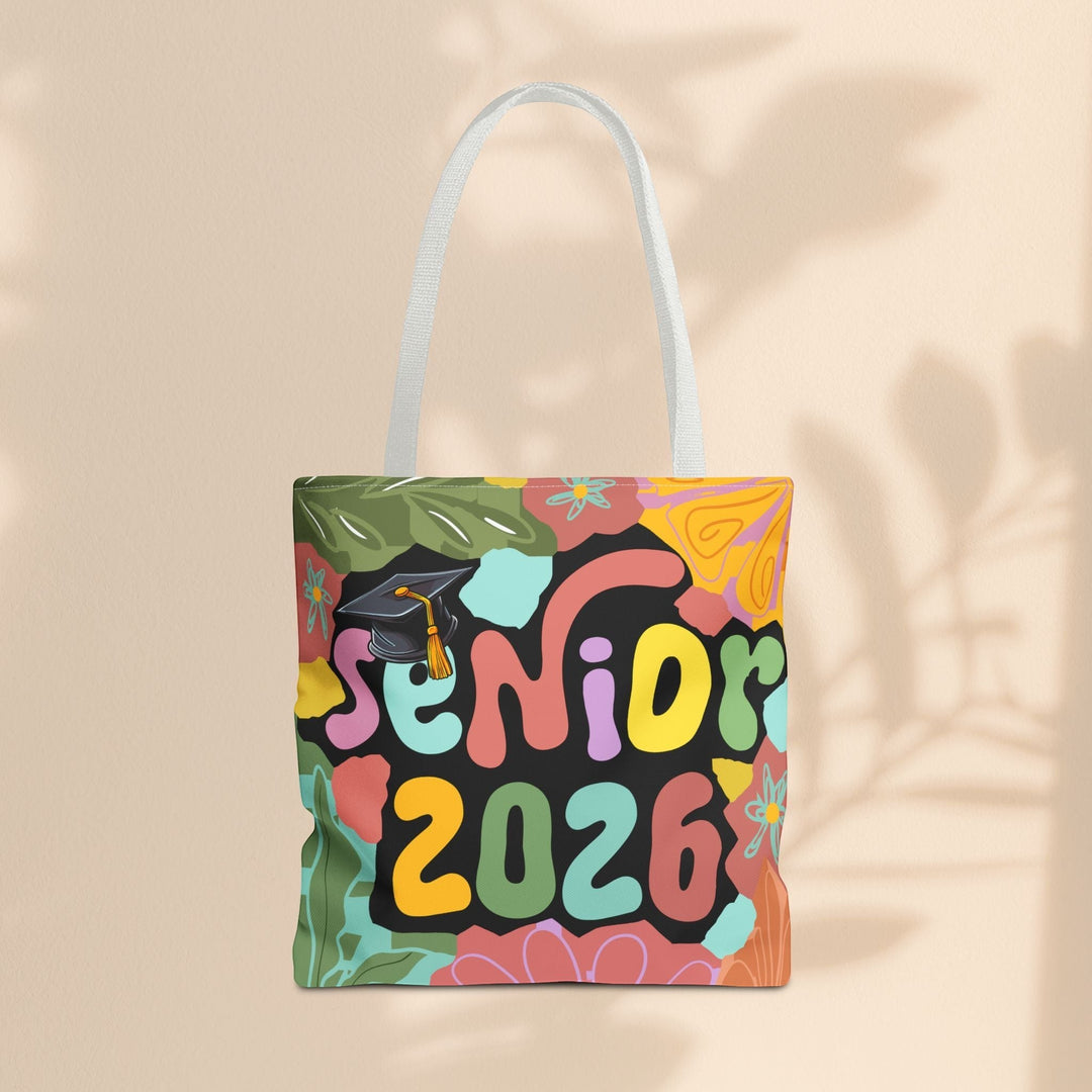Sea Dragon Dreams Senior 2026 tote bag with colorful floral print, graduation cap, and white handles on beige wall.