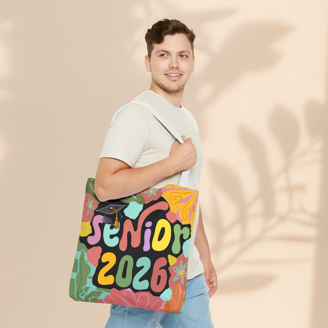 Sea Dragon Dreams Senior 2026 tote bag with colorful floral print and graduation cap, carried by a young man.