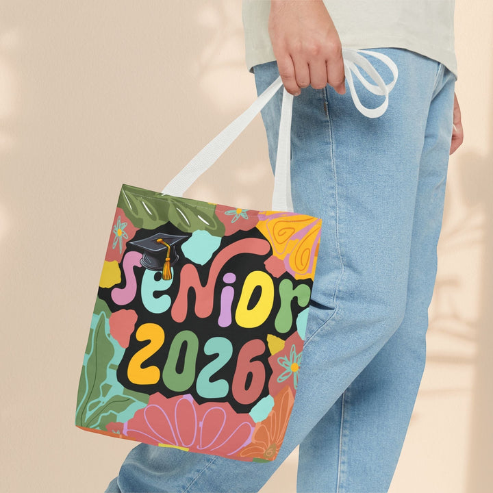 Sea Dragon Dreams Senior 2026 tote bag with colorful floral print and graduation cap, held by a person in jeans.
