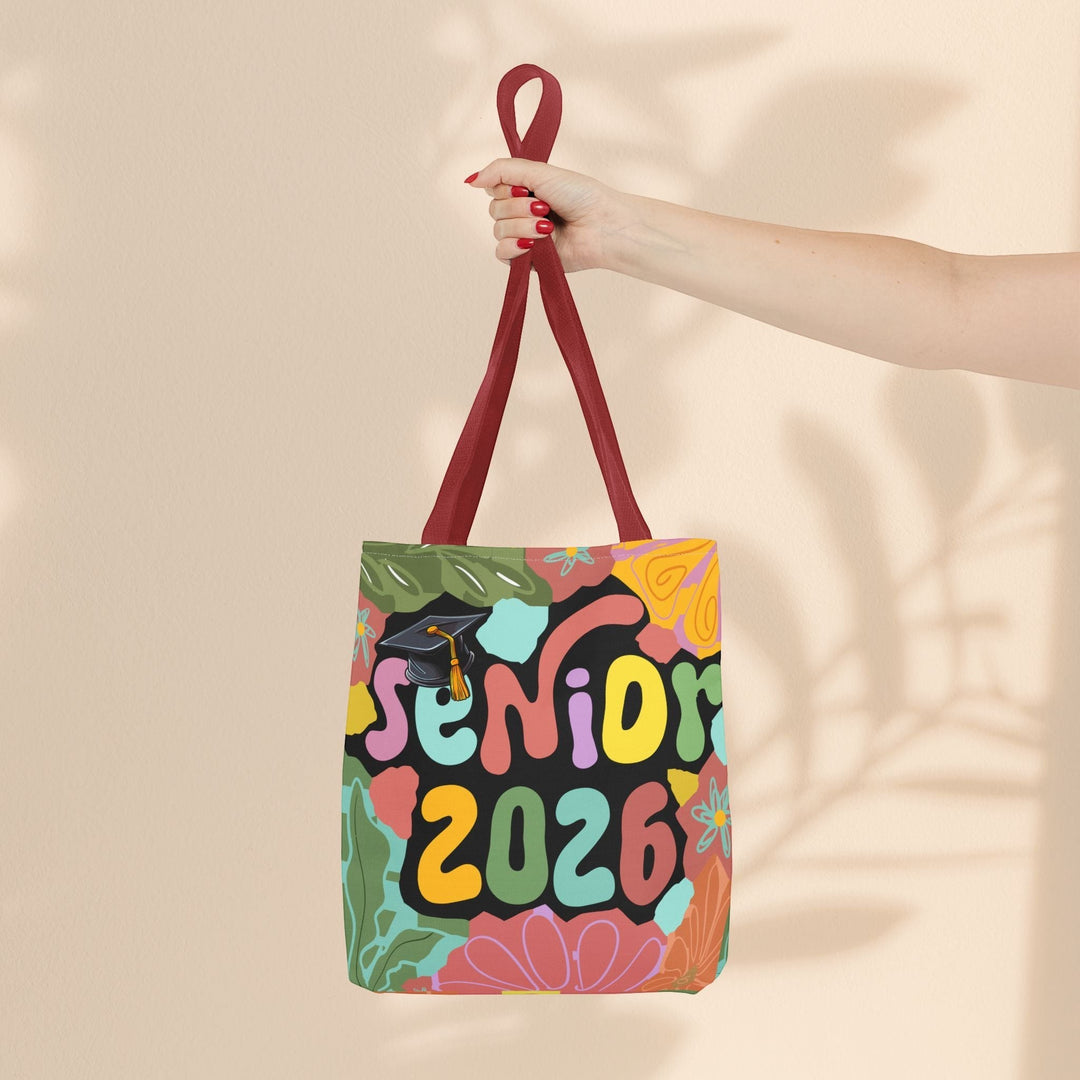 Sea Dragon Dreams Senior 2026 tote bag with colorful floral design and graduation cap held by a hand.
