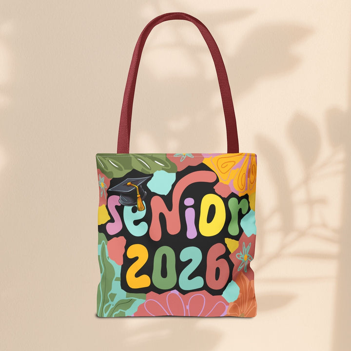 Sea Dragon Dreams Senior 2026 tote bag with colorful floral patterns, graduation cap graphic, and maroon handles.