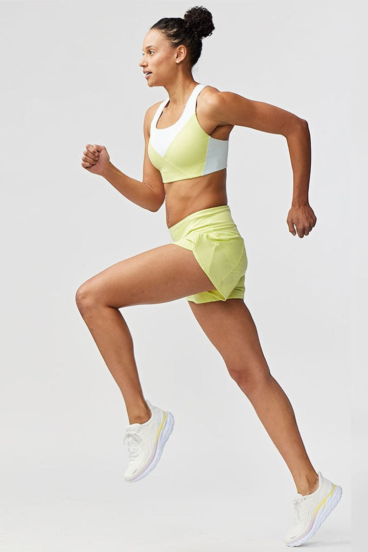 Sea Dragon Dreams Sheva high rise running shorts in light yellow worn by a female athlete running in profile view