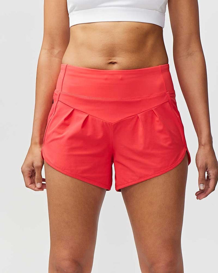 Sea Dragon Dreams Sheva high rise running shorts in bright coral with a flat knit waistband and pleated design.