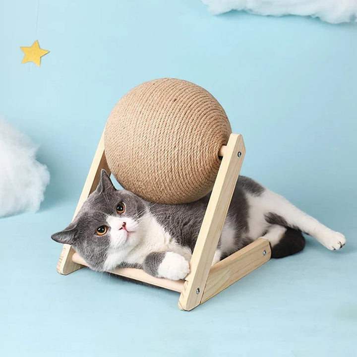 Sea Dragon Dreams cat scratching ball toy with natural sisal rope on a wooden base, featuring a grey cat resting below.