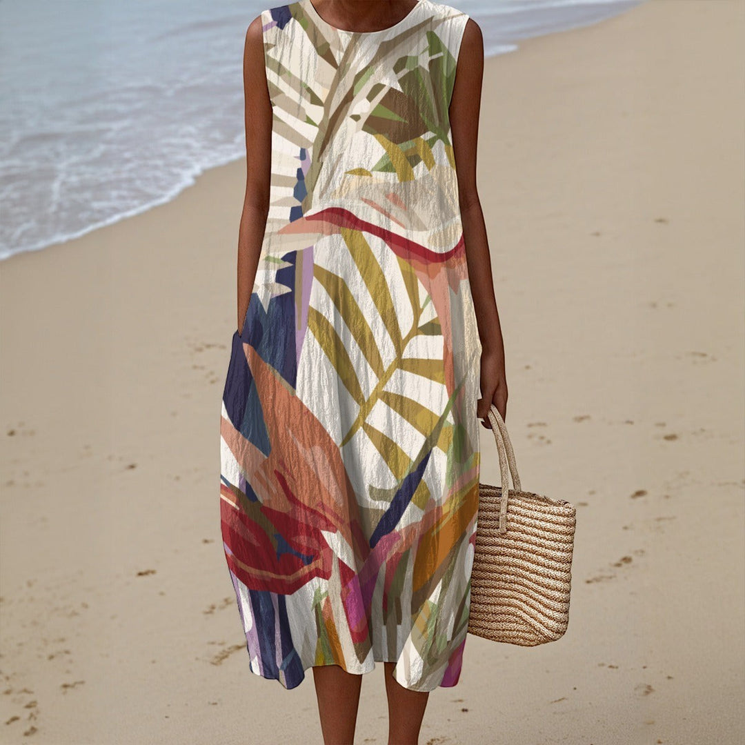 Sea Dragon Dreams sleeveless cotton slub summer dress with tropical leaf print and pocket, worn on a sandy beach.