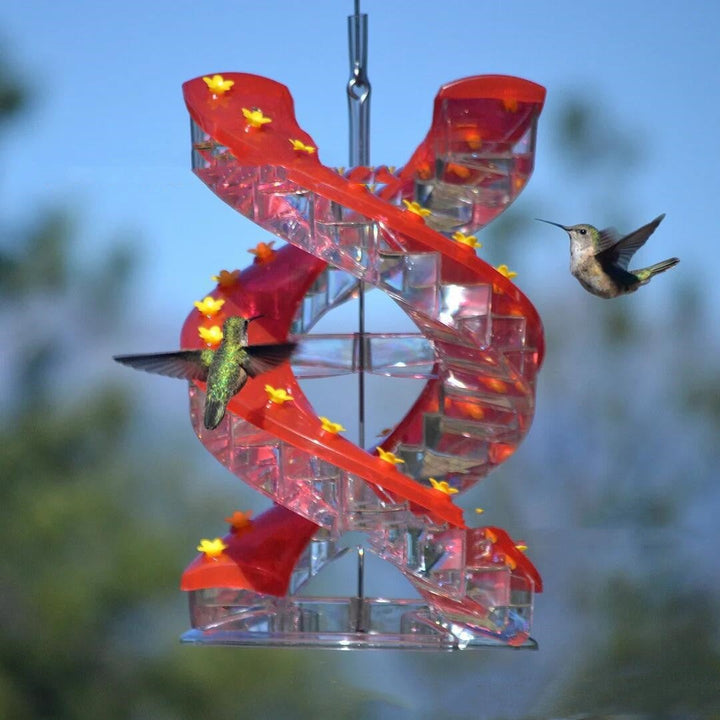 Sea Dragon Dreams red spiral hummingbird feeder with climbing perches and hummingbirds feeding in a garden setting