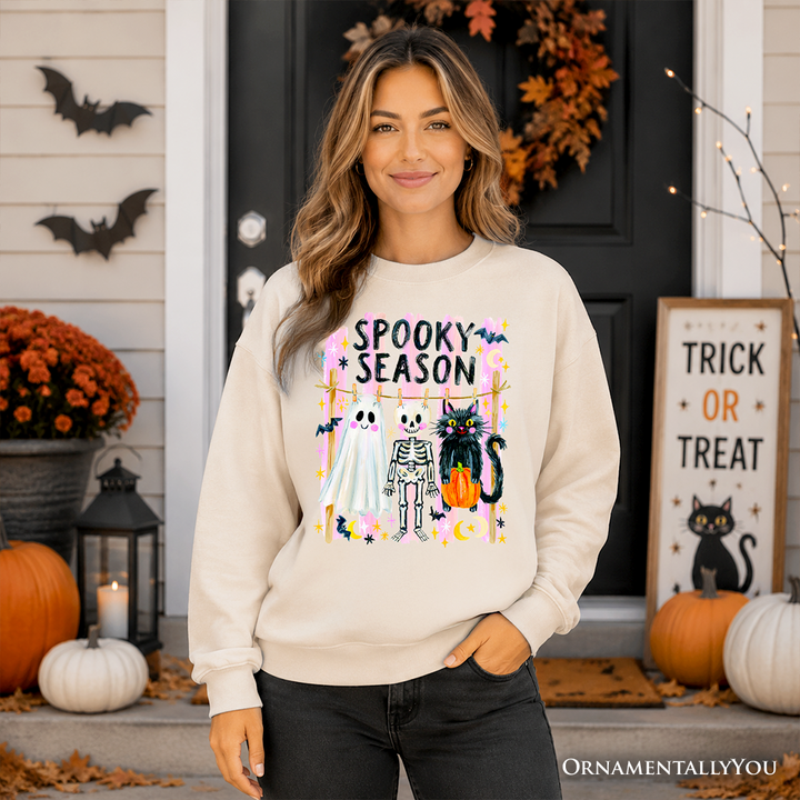 Sea Dragon Dreams beige sweatshirt featuring a colorful Spooky Season ghost, skeleton, and black cat graphic design.