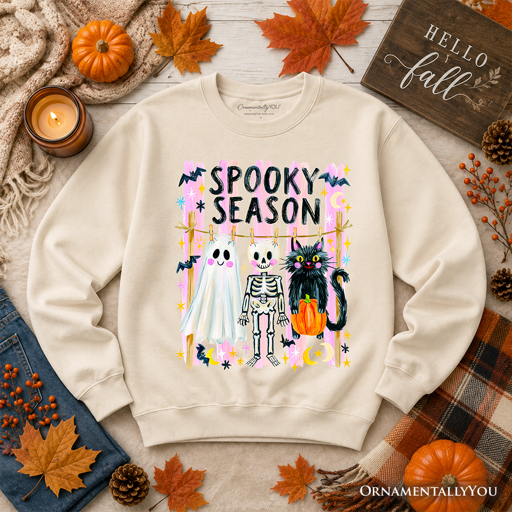 Sea Dragon Dreams beige sweatshirt featuring a colorful Spooky Season ghost, skeleton, and black cat graphic print.