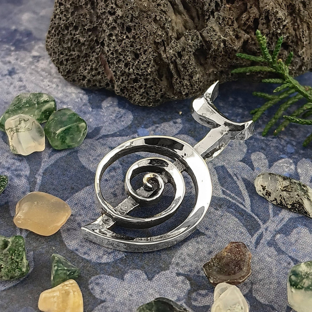 Sea Dragon Dreams handmade sterling silver Cho Ku Rei Reiki pendant with a sculptural spiral design on a patterned mat