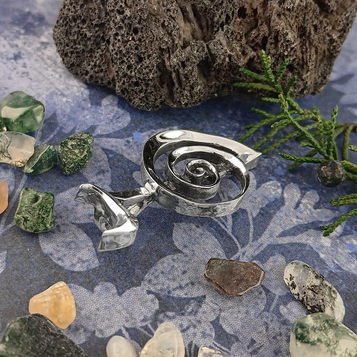Sea Dragon Dreams handmade sterling silver Cho Ku Rei Reiki pendant with a sculptural spiral design on a patterned mat.