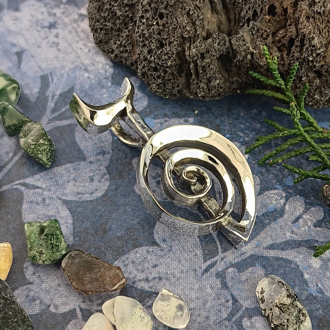 Sea Dragon Dreams sterling silver Cho Ku Rei Reiki pendant with a sculptural spiral design on a textured blue background.