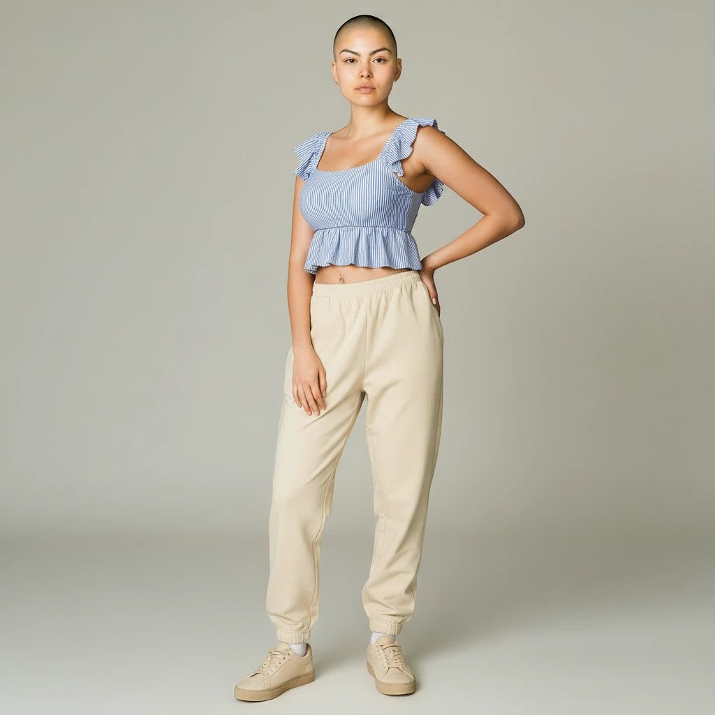 Model wearing a Sea Dragon Dreams blue striped ruffle-sleeve crop top with beige joggers and sneakers.