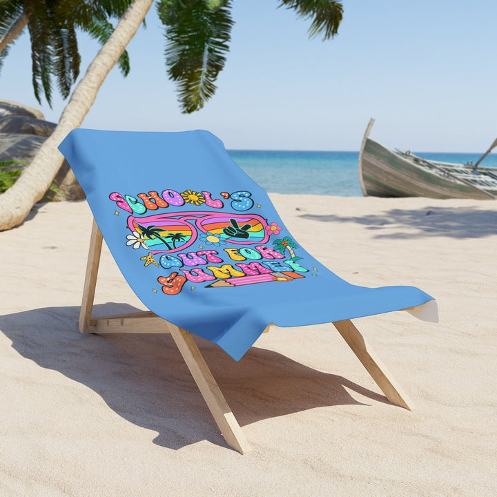 Sea Dragon Dreams School Is Out For Summer beach towel draped over a wooden lounge chair on a sunny tropical beach.