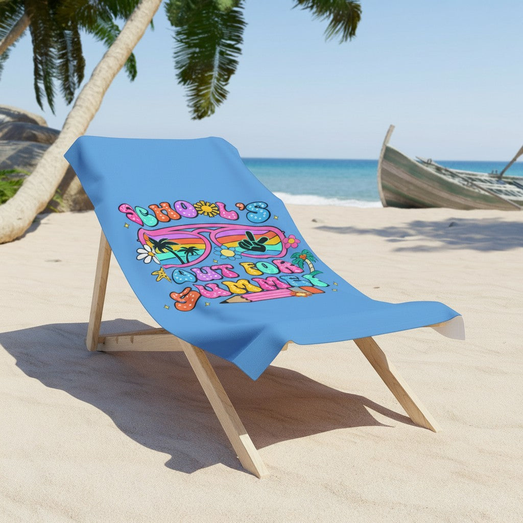 Sea Dragon Dreams School Is Out For Summer beach towel with vibrant graphic on a wooden chair at a sunny beach.