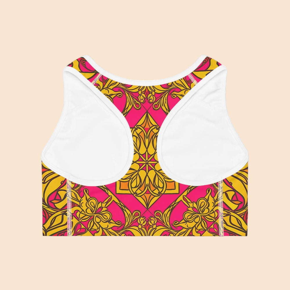 Sea Dragon Dreams Symmetry sports bra with a vibrant pink and gold geometric floral pattern and racerback design.