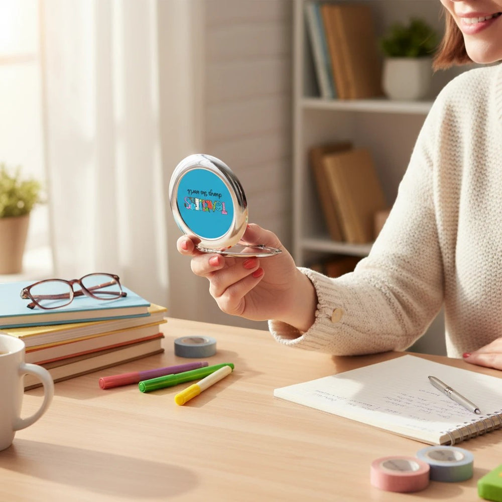 Sea Dragon Dreams Teachers Change The World compact travel mirror held by a woman at a desk with books and stationery.