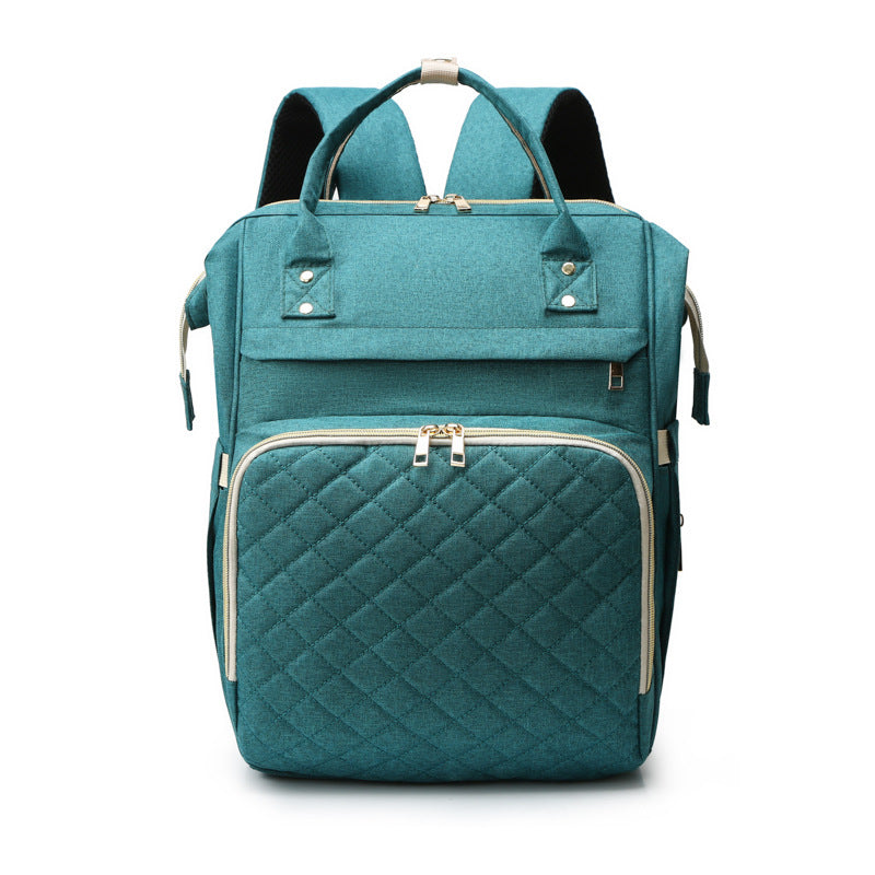 Sea Dragon Dreams teal diaper backpack with a quilted front pocket, gold zippers, and top carry handles.