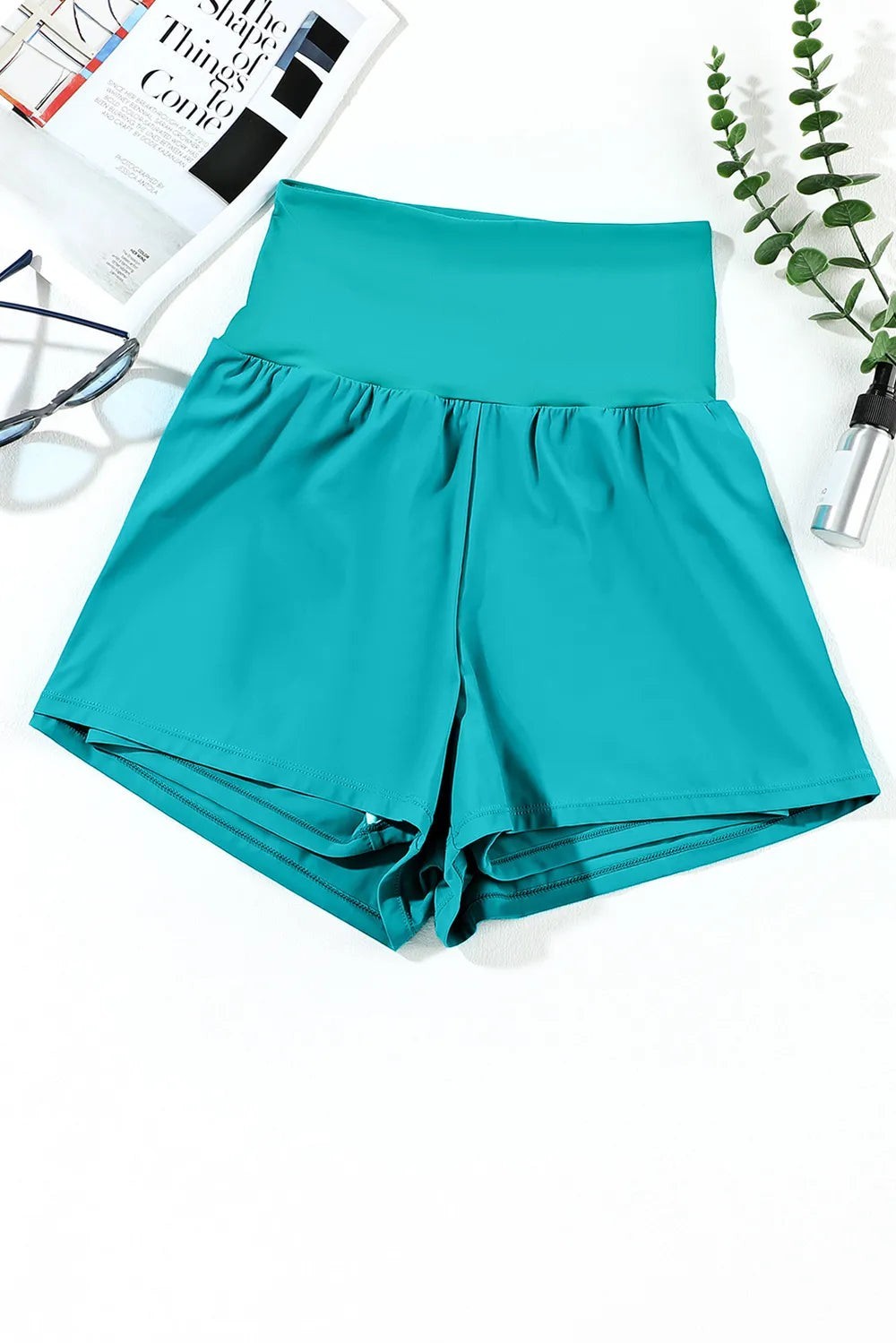 Sea Dragon Dreams high-waisted teal swim shorts with side pockets in a stretchy polyamide blend fabric.