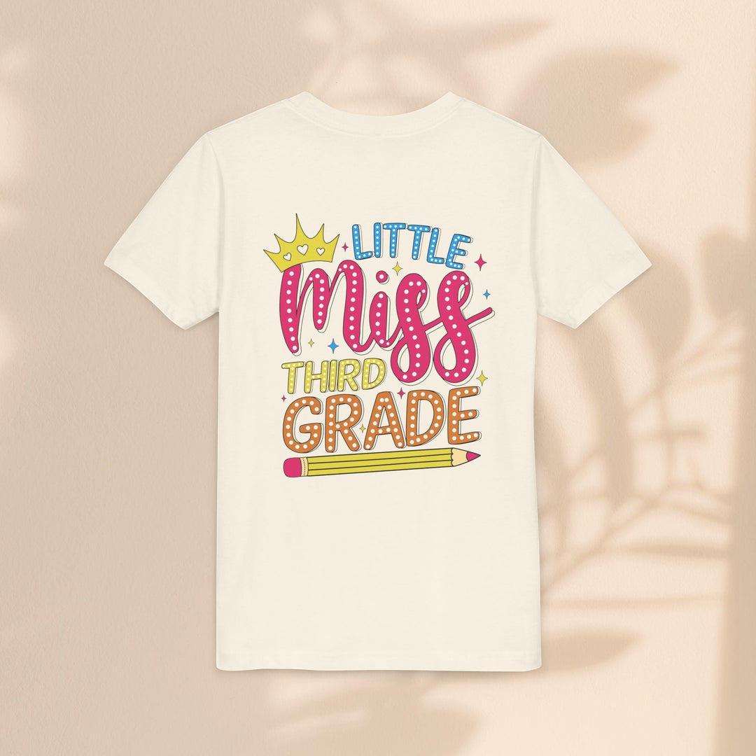 Sea Dragon Dreams youth tee in cream cotton featuring a Little Miss Third Grade graphic with a crown and pencil.