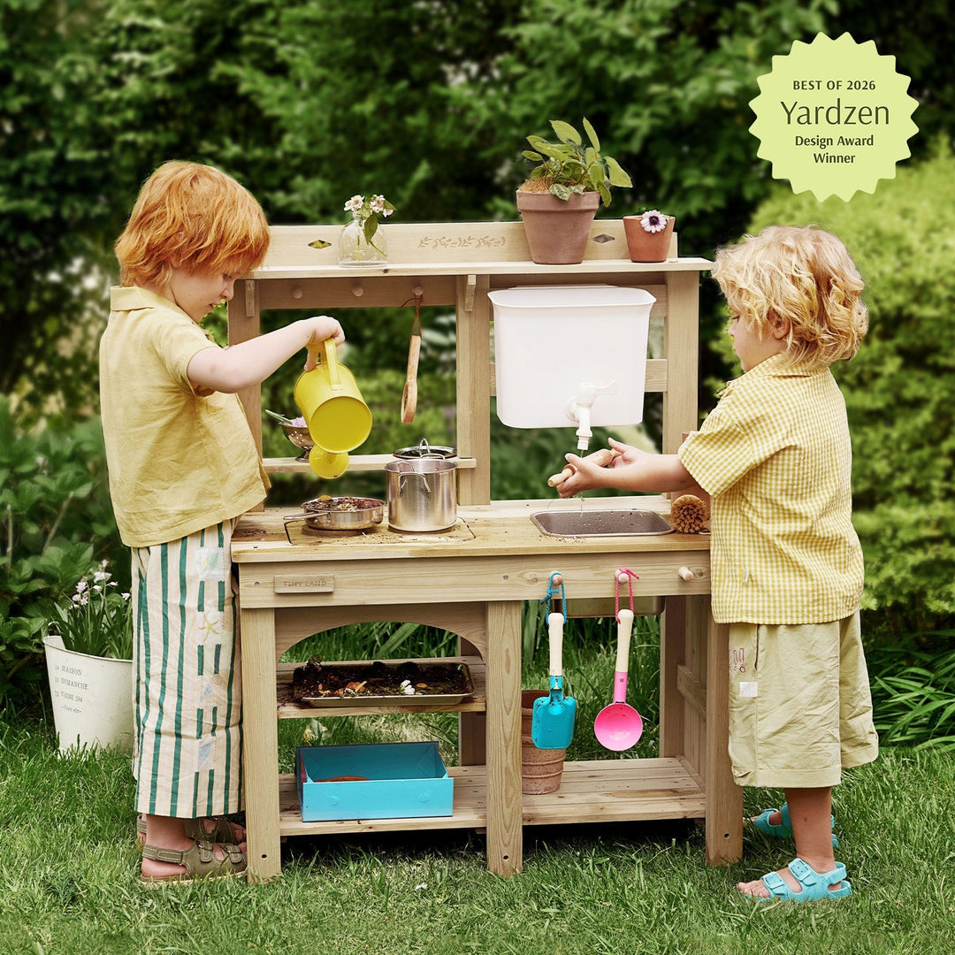 Sea Dragon Dreams Tiny Land mud kitchen with working faucet, sink, and storage, used by two children in a garden.