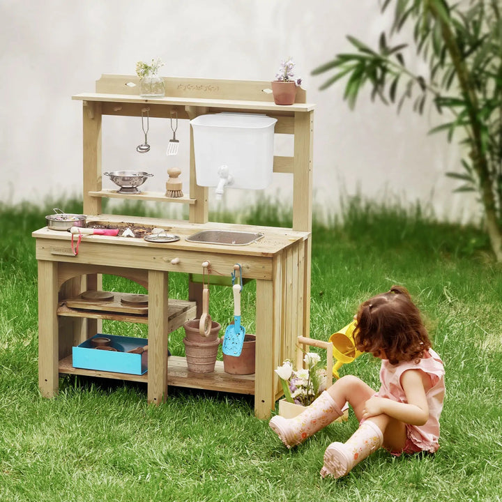Sea Dragon Dreams Tiny Land wooden mud kitchen with water tank and sink, played with by a child in a grassy backyard.