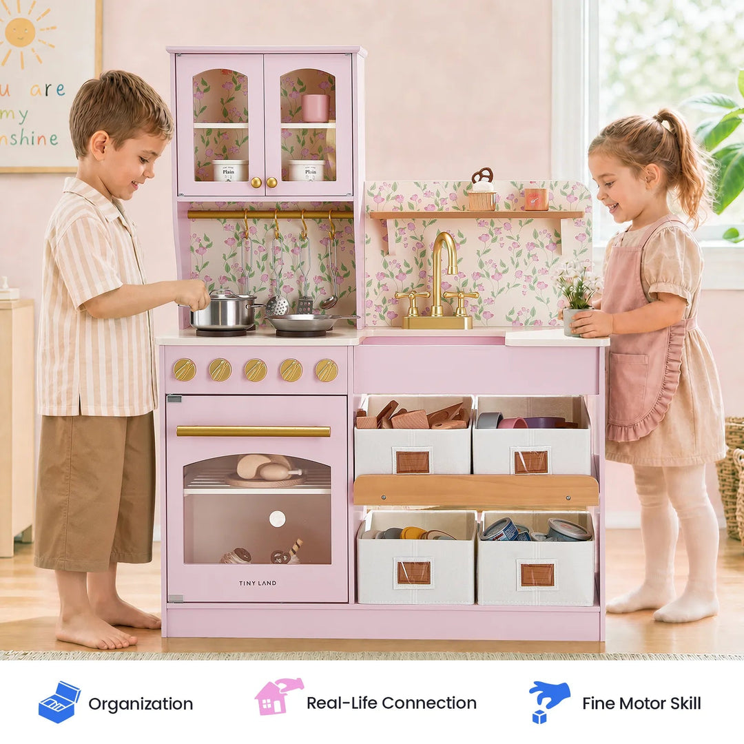 Sea Dragon Dreams Tiny Land wooden play kitchen in Sakura Pink with floral wallpaper, gold accents, and storage bins.