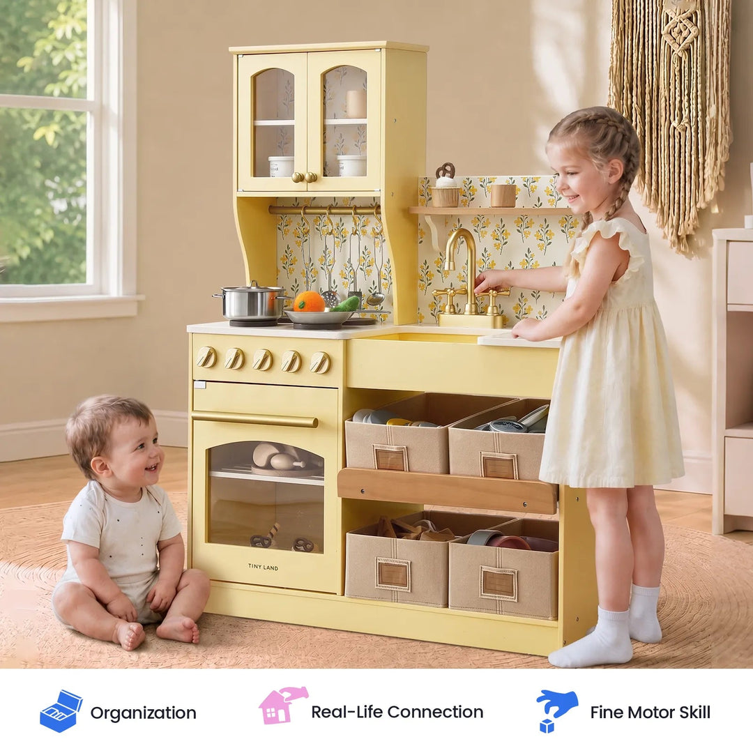 Sea Dragon Dreams Tiny Land wooden play kitchen in pale yellow with a young girl playing and a baby sitting nearby