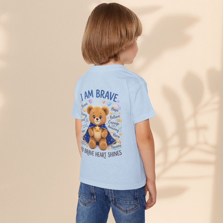 Child wearing a light blue Sea Dragon Dreams toddler t-shirt with a teddy bear graphic and I Am Brave text on back