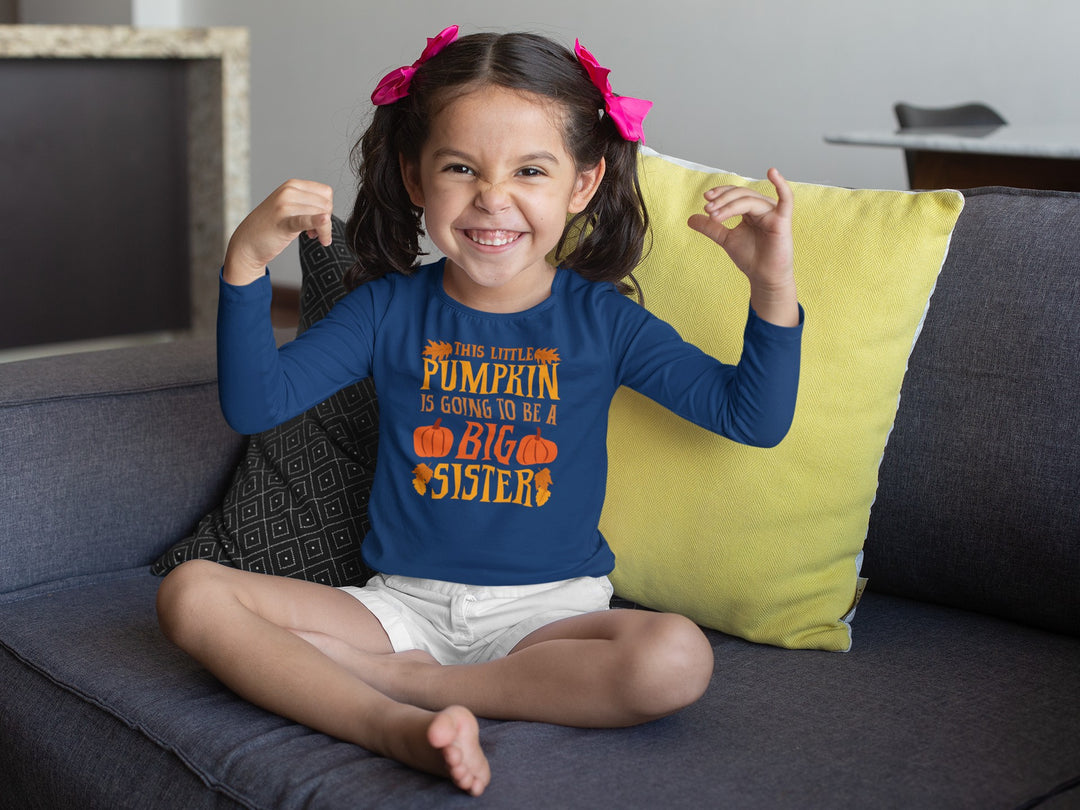 Sea Dragon Dreams toddler long sleeve blue cotton tee with Big Sister Pumpkin graphic, worn by a smiling girl.