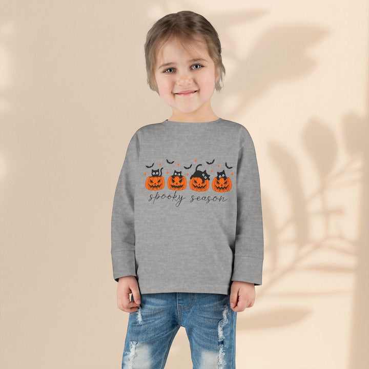 Sea Dragon Dreams toddler wearing a grey long sleeve Halloween tee with a pumpkin and black cat spooky season print.