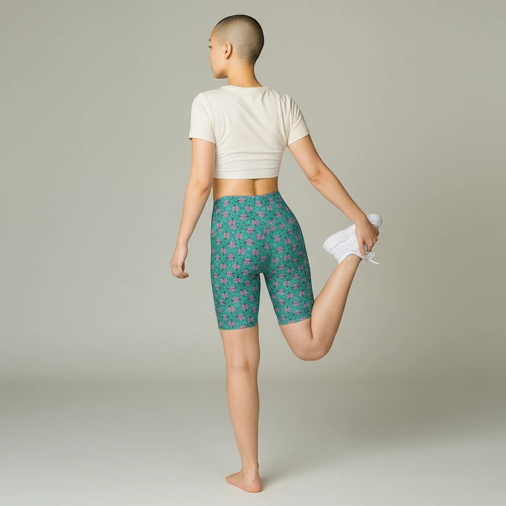 Sea Dragon Dreams women's tropical print activewear shorts in green, worn by a model stretching in a studio.
