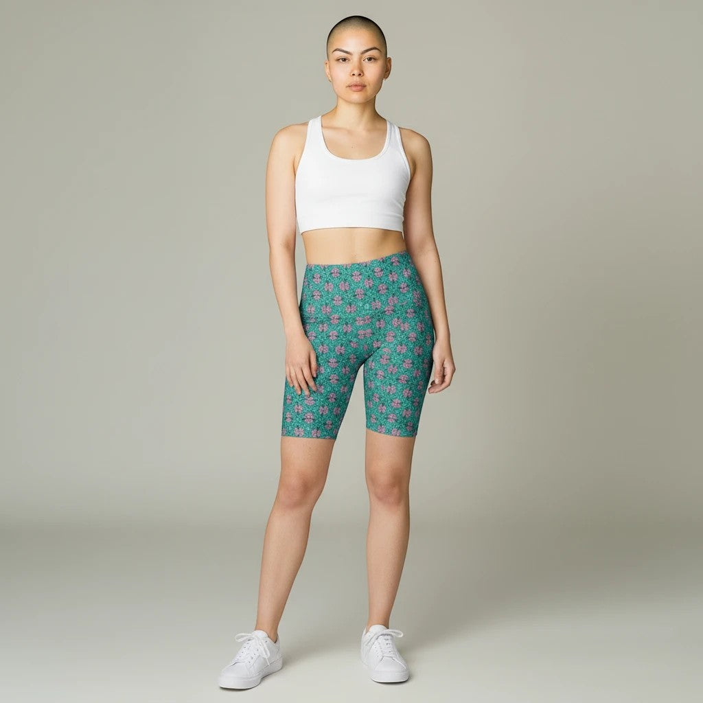 Sea Dragon Dreams women's tropical print workout shorts in teal and pink, paired with a white sports bra.