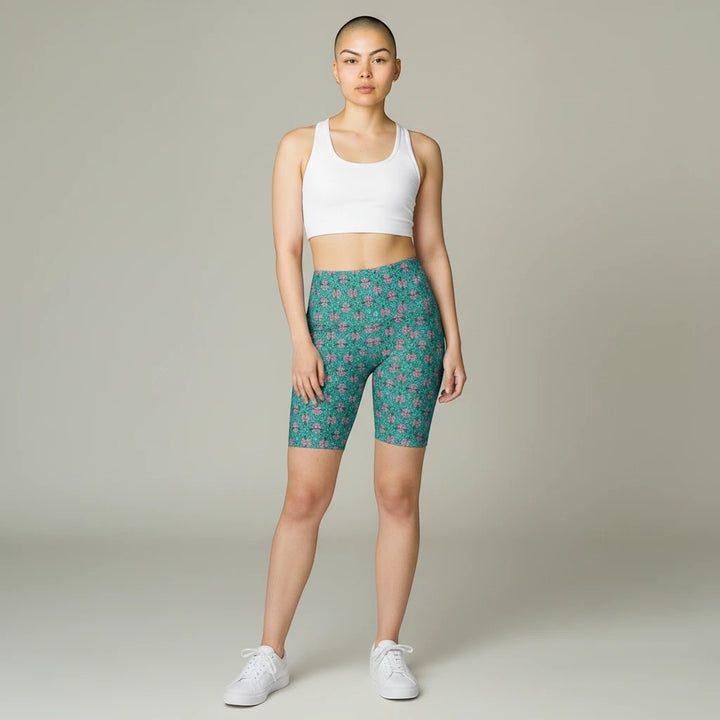 Sea Dragon Dreams women's tropical print workout shorts in teal and pink, paired with a white sports bra.