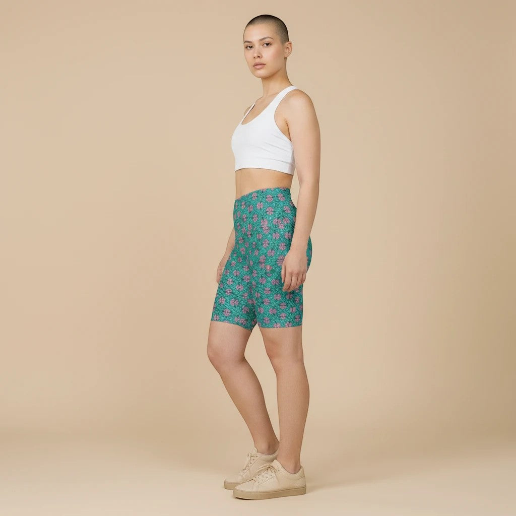 Sea Dragon Dreams women's tropical print workout shorts in green and pink polyester, worn with a white sports bra.