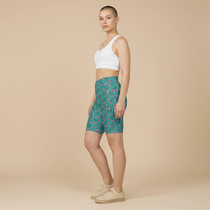 Sea Dragon Dreams women's tropical print workout shorts in green and pink polyester, worn with a white sports bra.