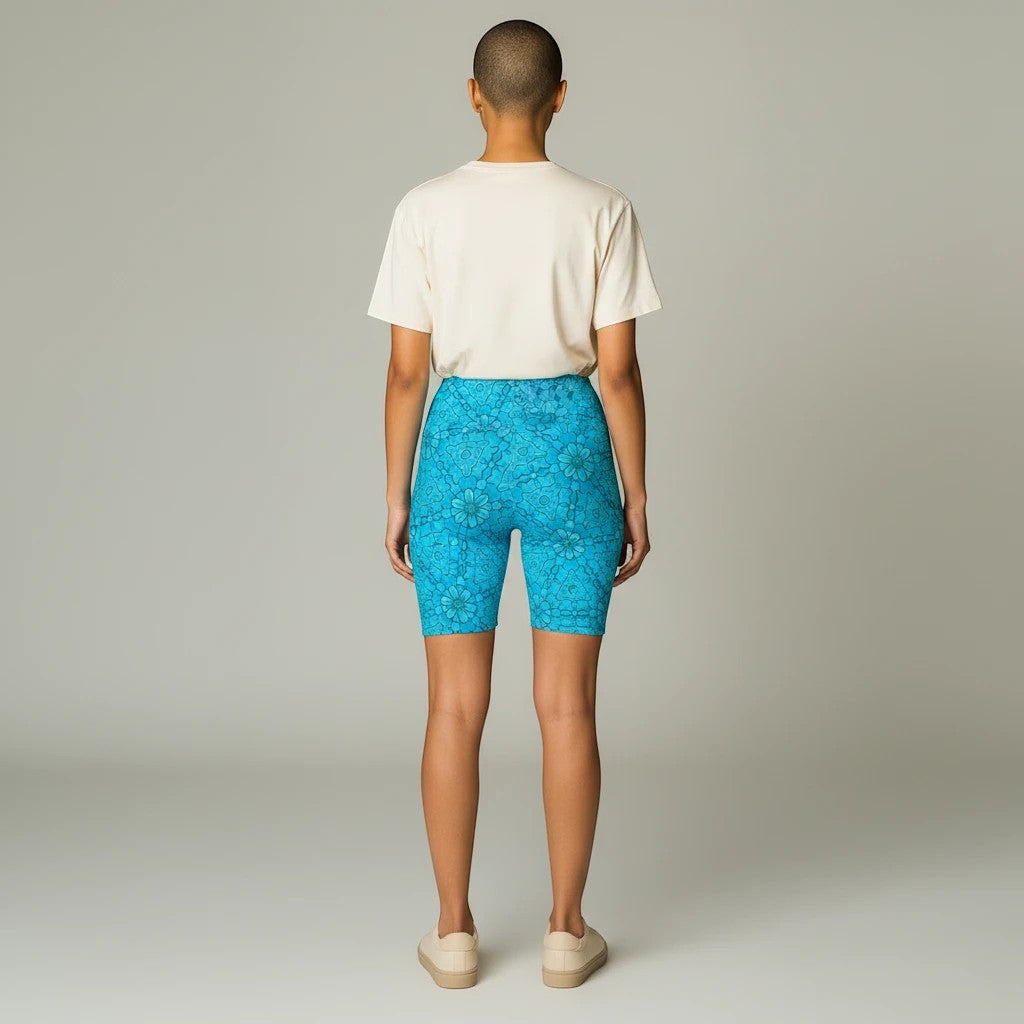 Back view of a model wearing Sea Dragon Dreams turquoise groovy print workout shorts with a beige t-shirt