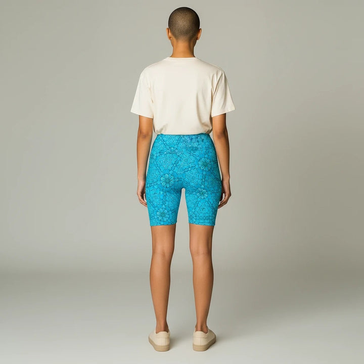 Back view of a model wearing Sea Dragon Dreams turquoise groovy print workout shorts with a beige t-shirt