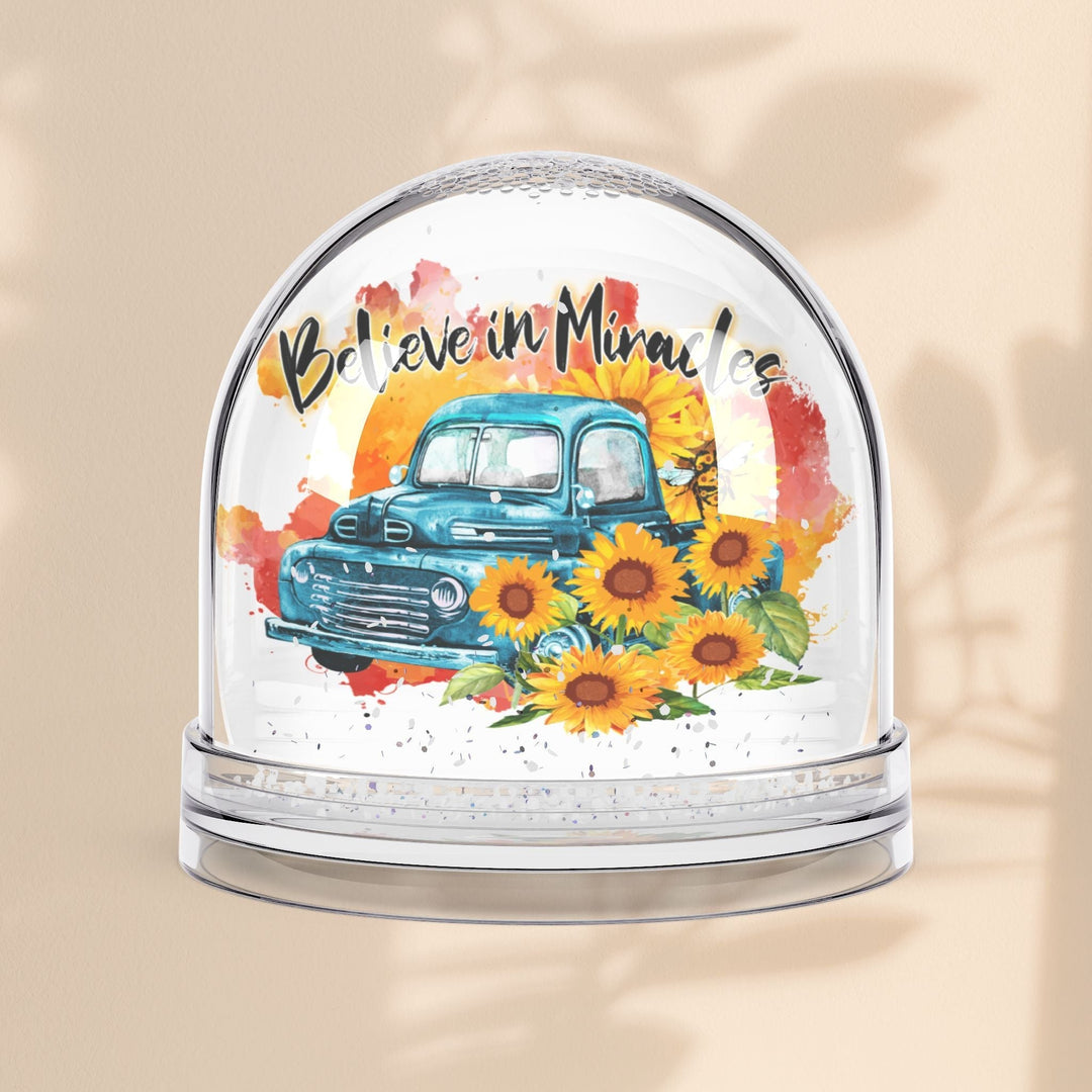 Sea Dragon Dreams Believe in Miracles snow globe featuring a vintage blue truck and sunflowers on a beige background.